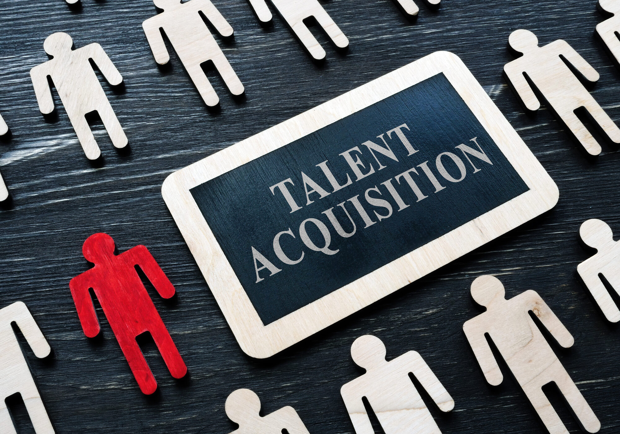 Talent acquisition concept. Small plaque and wooden figures.