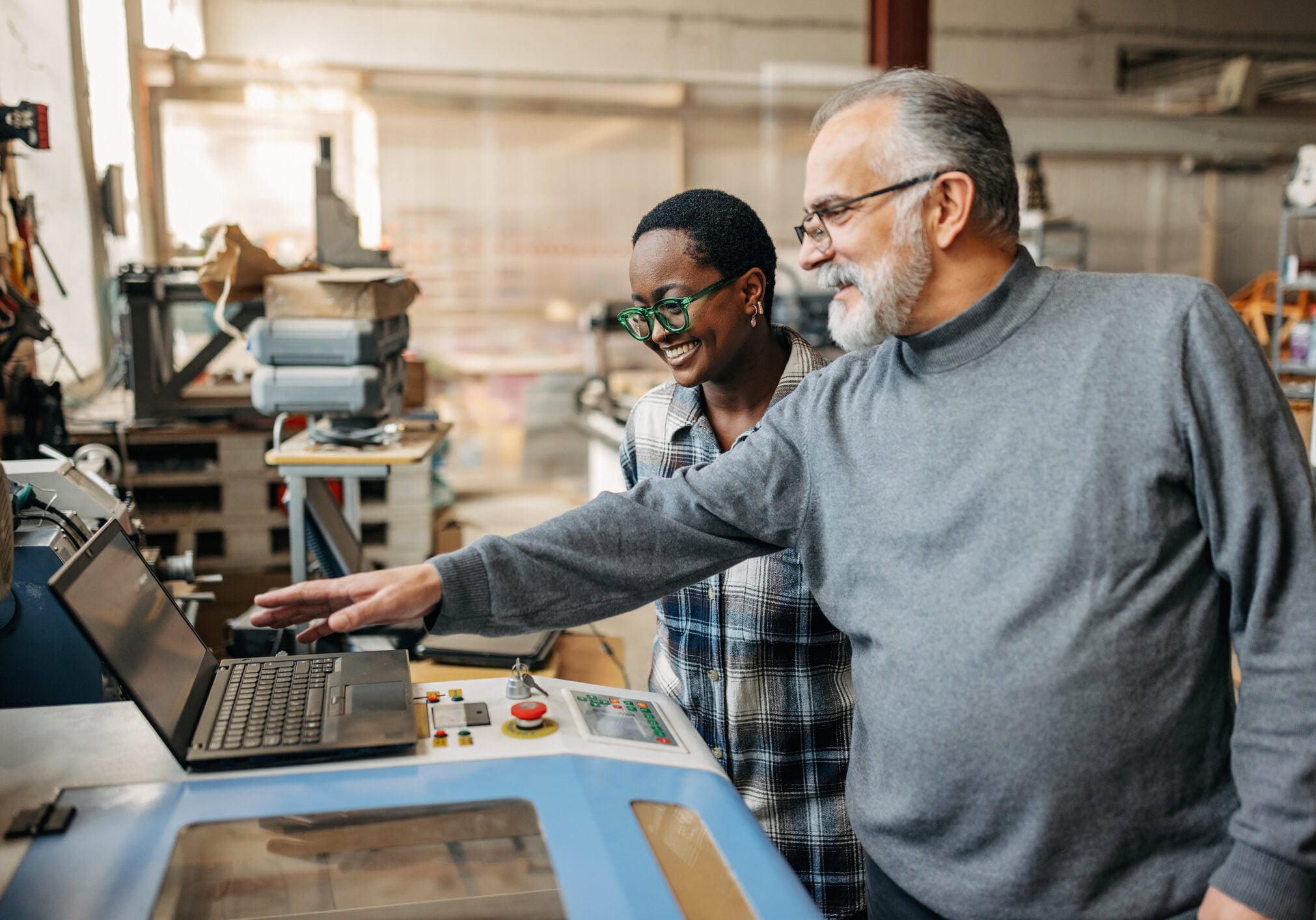 Mid adult man explaining laser cut machine to a black female student